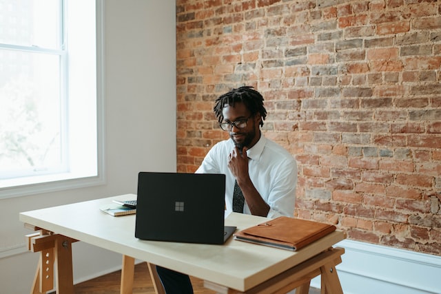 seorang pria sedang duduk bekerja dengan laptop